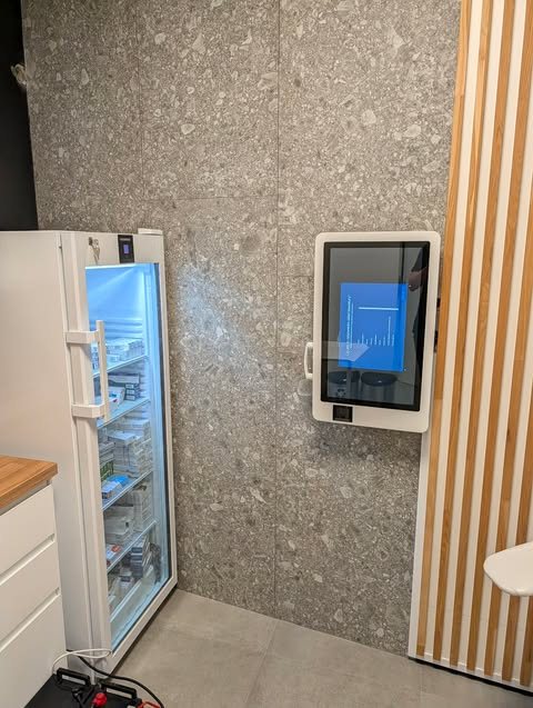 Kiosk szczepień zamontowany na ścianie obok lodówki ze szczepionkami